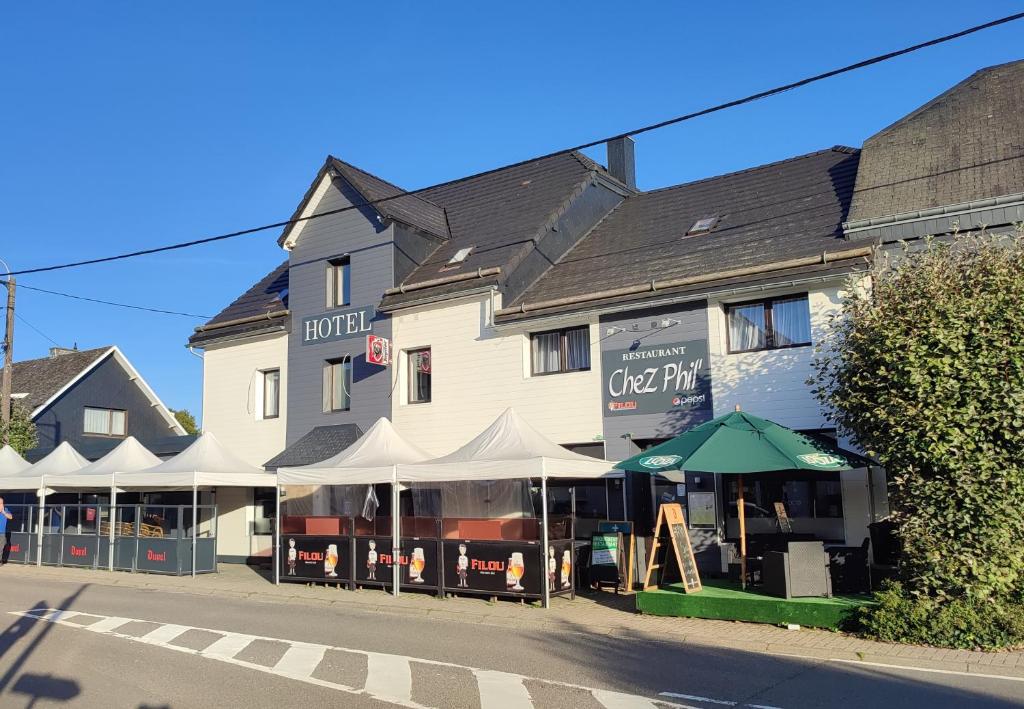 un grand bâtiment blanc avec un café dans une rue dans l'établissement Chez Phil, à Robertville