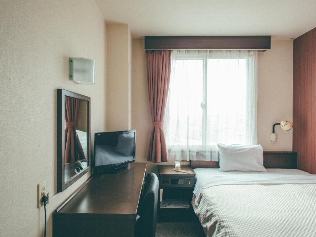 una camera d'albergo con letto, scrivania e finestra di Toyohashi Station Hotel / Vacation STAY 66965 a Toyohashi