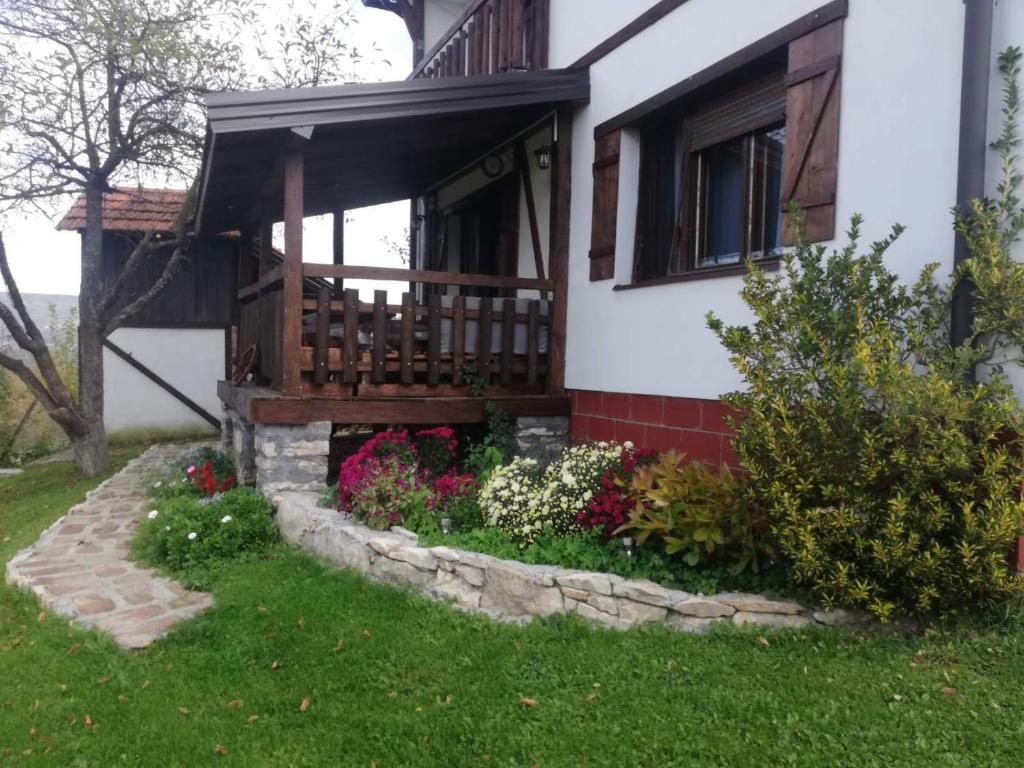 une maison avec terrasse couverte et fleurs dans la cour dans l'établissement Vikendica i vajat Vrbica, à Kalesija