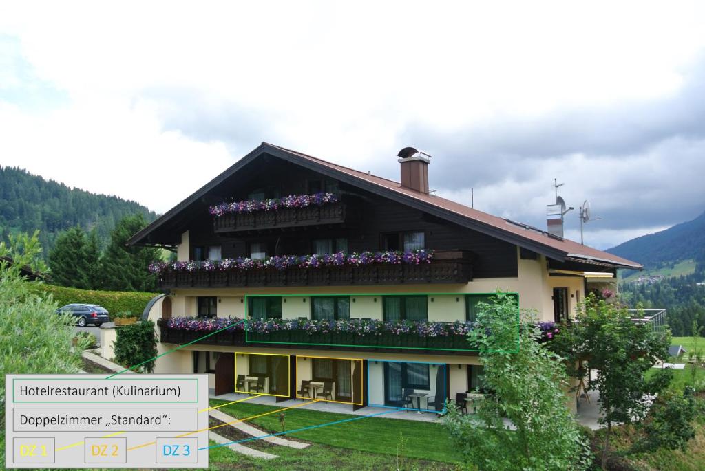 a building with flowers on the balcony of it at Boutique Hotel Herzhof - Garni-Appartements - Adults Only in Riezlern