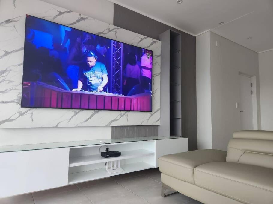 sala de estar con TV de pantalla plana en la pared en Ballito Hills Lifestyle Estate Unit 423, en Ballito