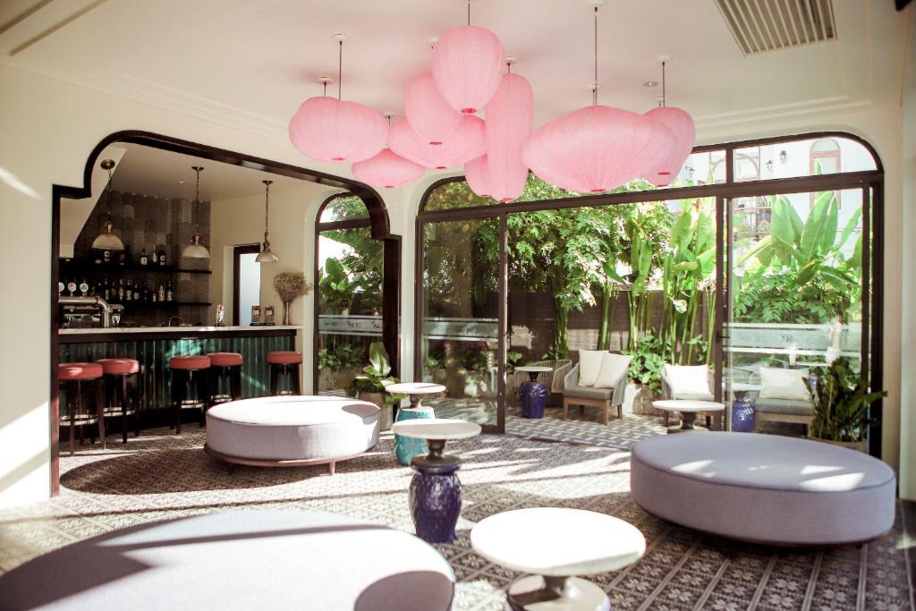 a lobby with tables and chairs and pink lighting at De An Hotel in Hoi An