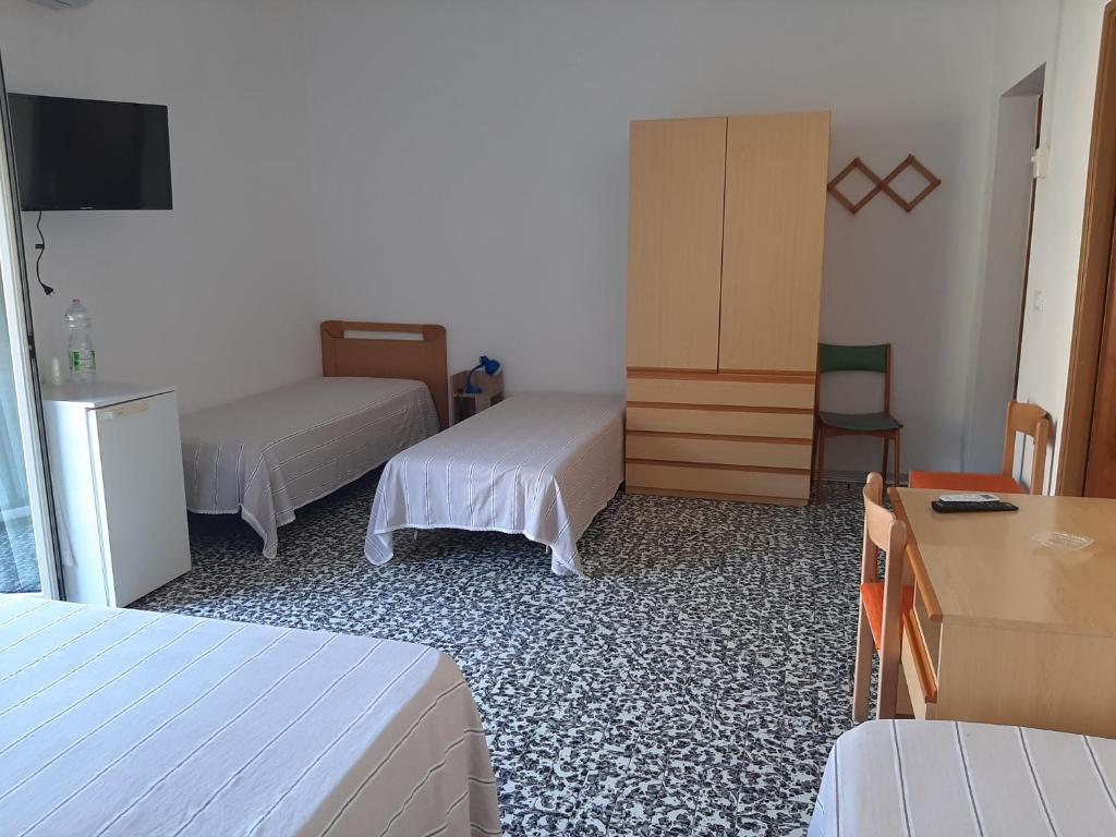 a hotel room with two beds and a table and a desk at Hotel Conca d'Oro in Stalettì