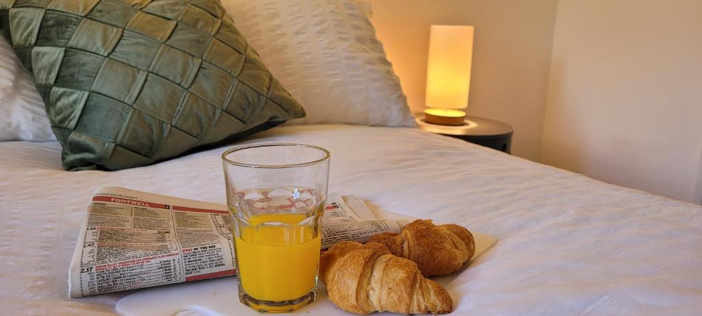 a glass of orange juice and bread and a newspaper on a bed at 1st Floor Flat Bennetthorpe Overlooking Doncaster Racecourse Free Parking in Doncaster