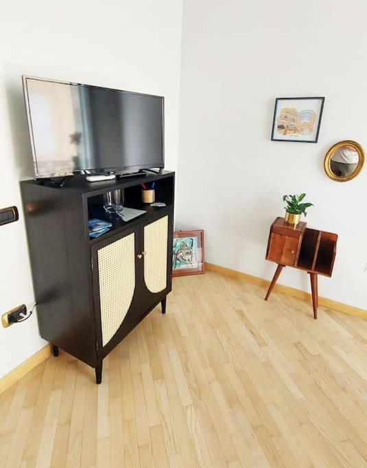 salon z telewizorem z płaskim ekranem i drewnianą podłogą w obiekcie Maison In Centro w mieście Neapol