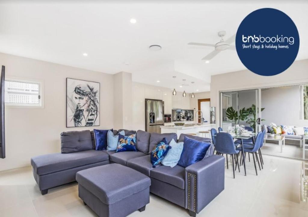 a living room with a blue couch and a dining room at Park Avenue Luxe Townhouse Brand New Sleeps 9 in Brisbane