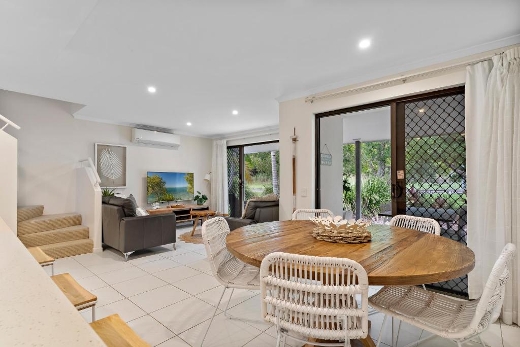 a living room with a wooden table and chairs at Tropical Retreat in 2 Bedroom Townhouse in Noosaville