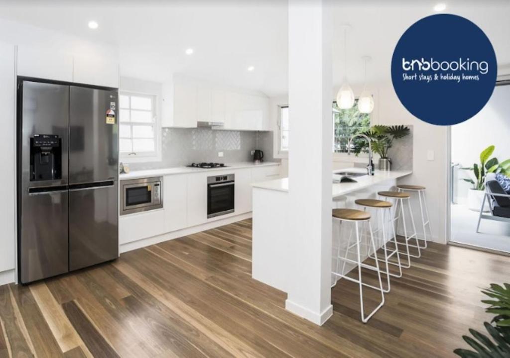eine Küche mit einem Kühlschrank und einer Theke mit Stühlen in der Unterkunft Park Avenue Terrace House Sleeps 9 in Brisbane