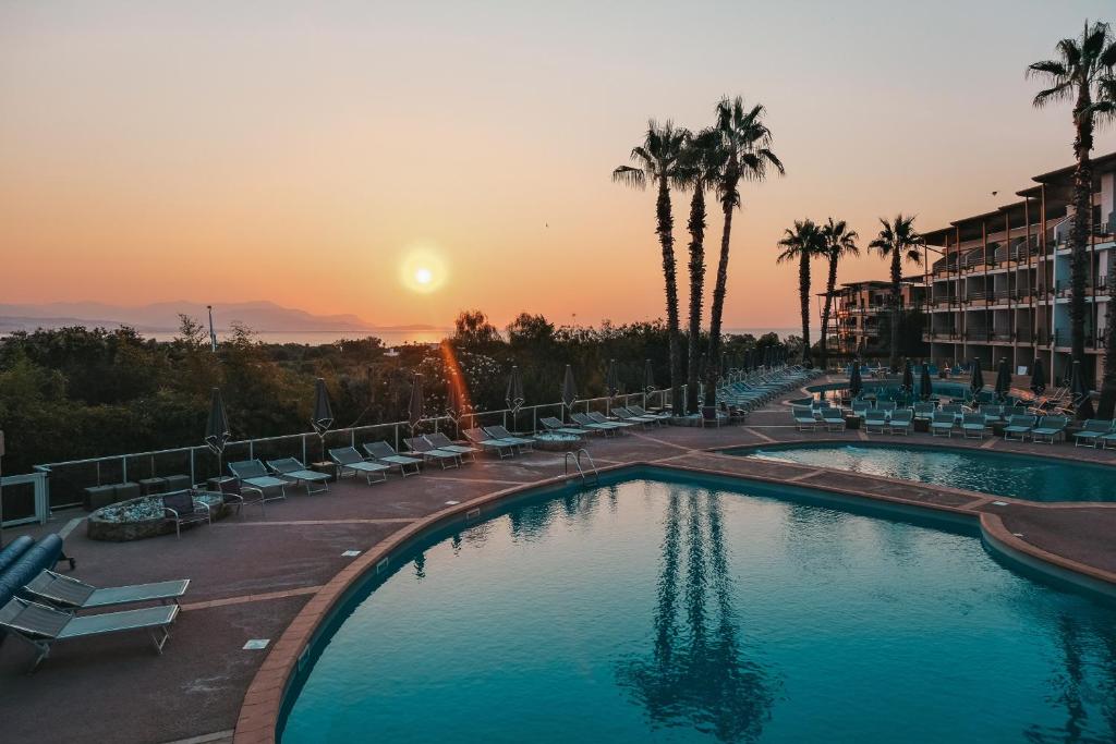 a large pool with chairs and palm trees at sunset at Thalazur Antibes - Résidence & Spa in Antibes