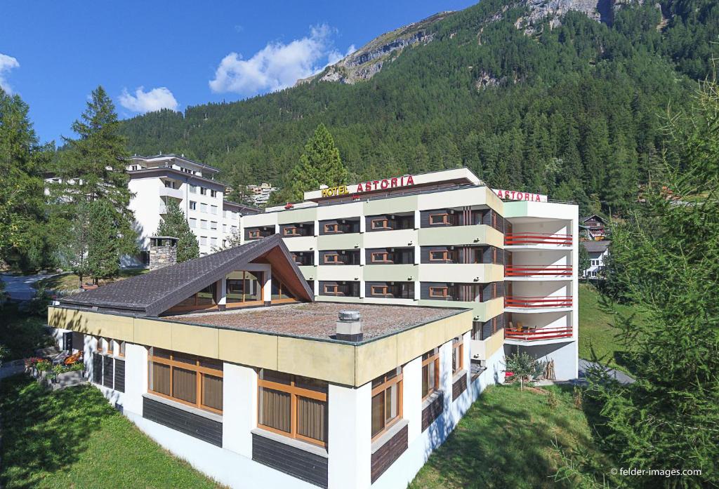 un bâtiment d'hôtel avec une montagne en arrière-plan dans l'établissement Hotel Astoria, à Loèche-les-Bains