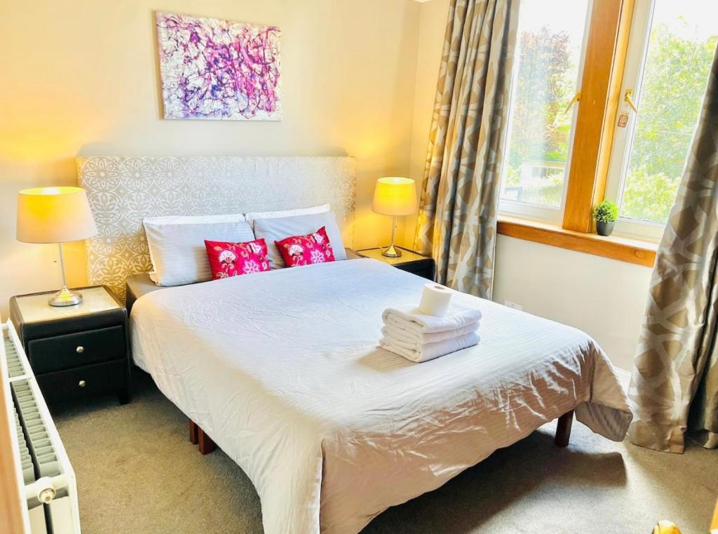 Schlafzimmer mit einem Bett mit roten Kissen und einem Fenster in der Unterkunft LEITH WALK VILLA budget guest house in Edinburgh
