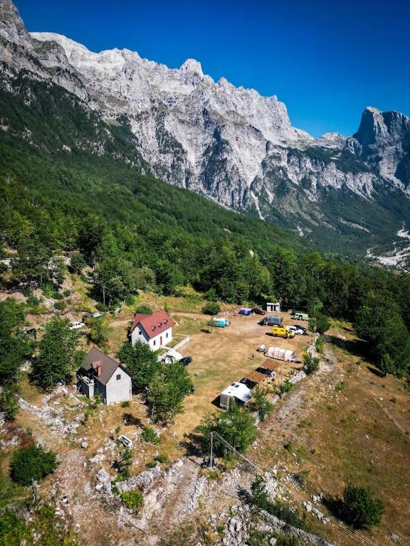un gruppo di case su un campo con una montagna di Guesthouse Freskia a Theth