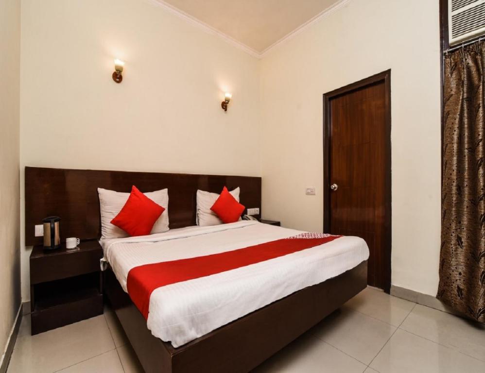 a bedroom with a large bed with red pillows at Hotel Delight Inn, Amritsar in Amritsar