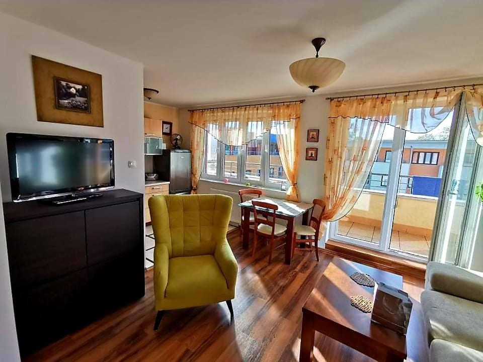 a living room with a yellow chair and a television at Słoneczny Apartament in Kołobrzeg