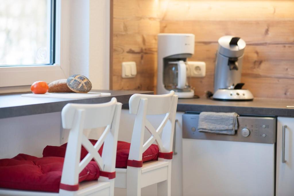 - deux chaises blanches dans une cuisine avec un comptoir dans l'établissement Apartment an der Wurmbergseilbahn 2, à Braunlage
