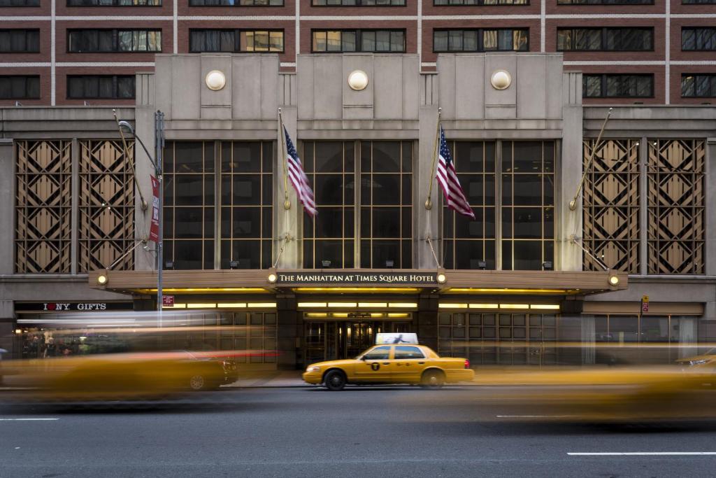 un taxi amarillo frente a un edificio con banderas americanas en The Manhattan at Times Square, en Nueva York