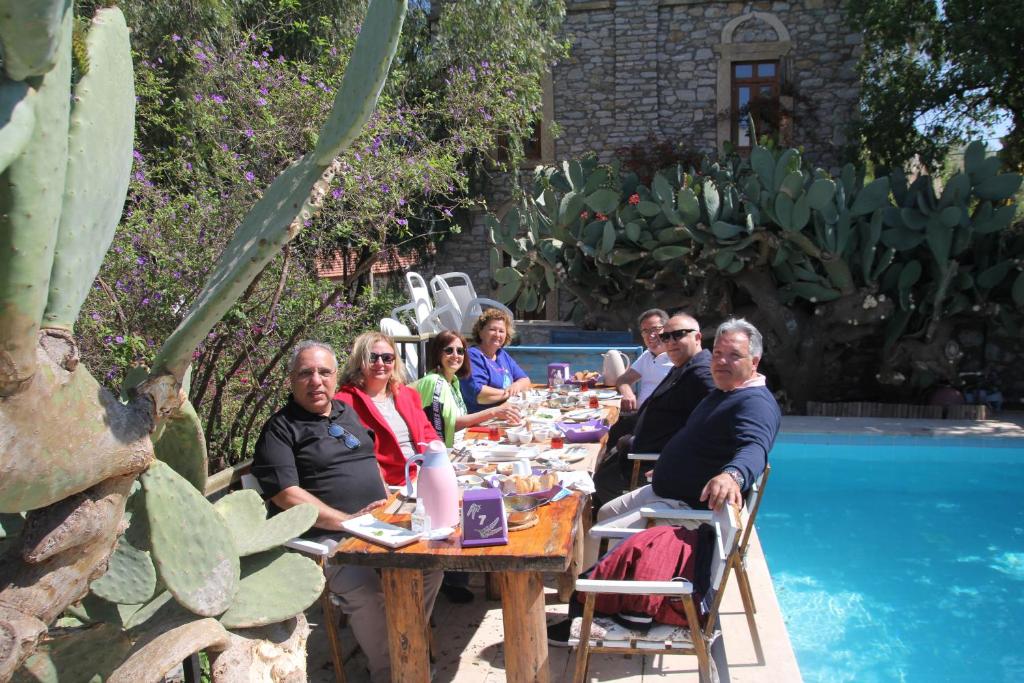 een groep mensen aan een tafel bij een zwembad bij Eski Datça Pansiyon in Datca