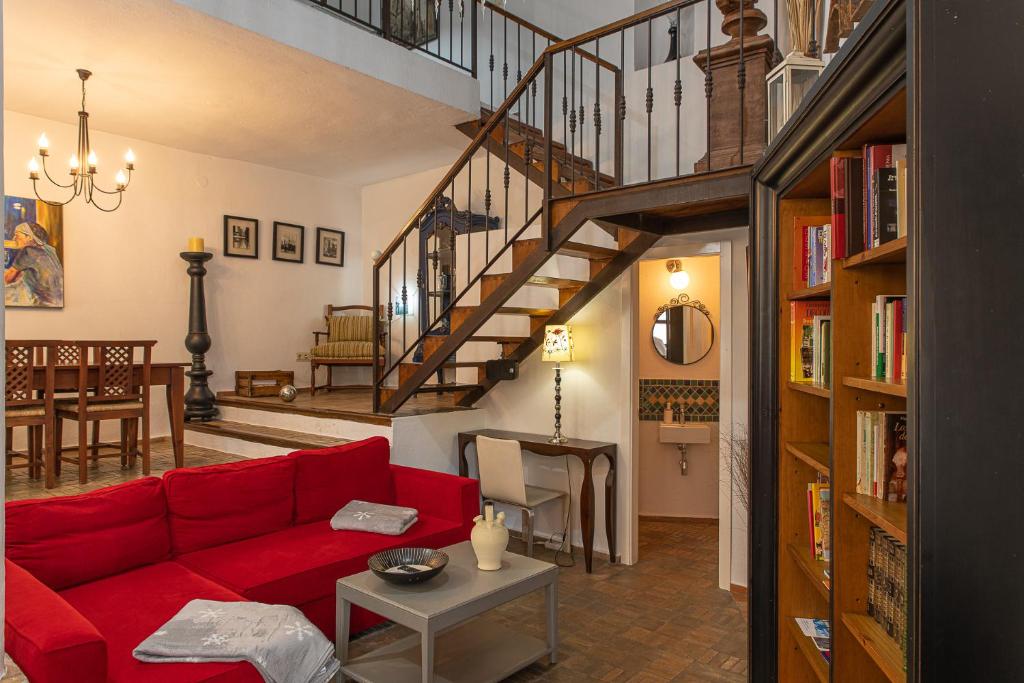 a living room with a red couch and a staircase at El Pensamiento Duplex in Ronda