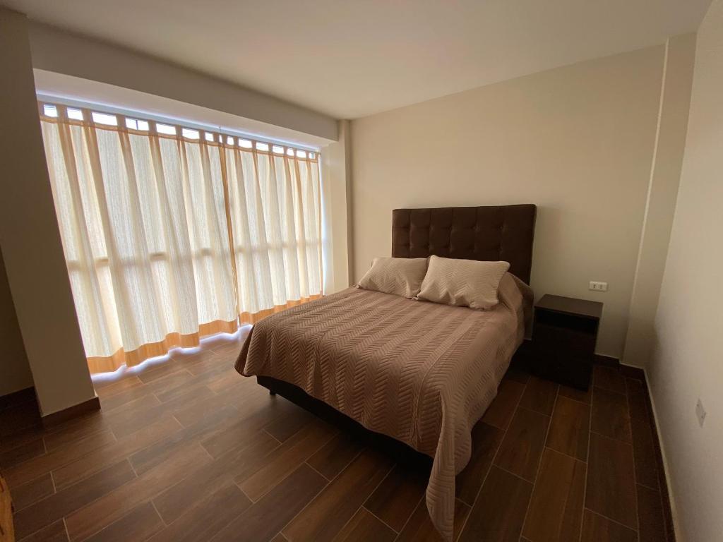 a bedroom with a bed and a large window at Agradable departamento con estacionamiento gratis in Sucre
