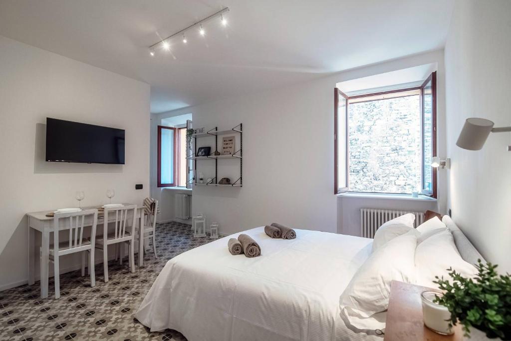 a white bedroom with a bed and a tv at Cesare 22 - The House Of Travelers in Como