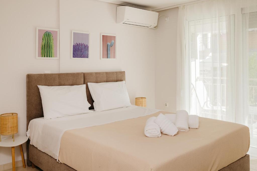 um quarto branco com uma cama grande e almofadas brancas em CACTUS - Blooming Garden Apartments em Kalamata