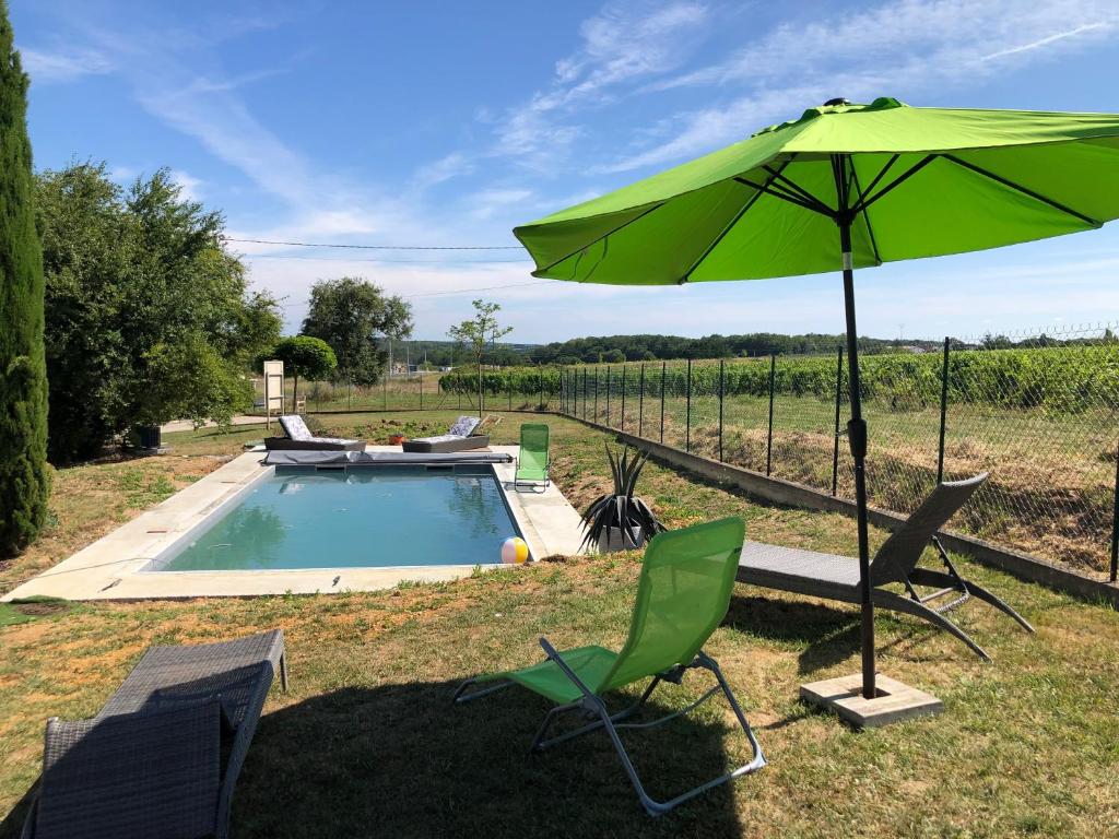 - un parasol vert et des chaises à côté de la piscine dans l'établissement Gîte Lady Adra, à Saint-Aignan