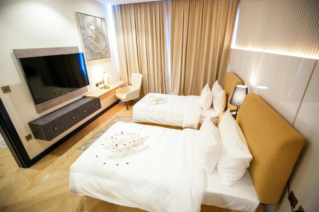 A&H Hotel Apartment في الدوحة: غرفة فندقية بسريرين وتلفزيون بشاشة مسطحة