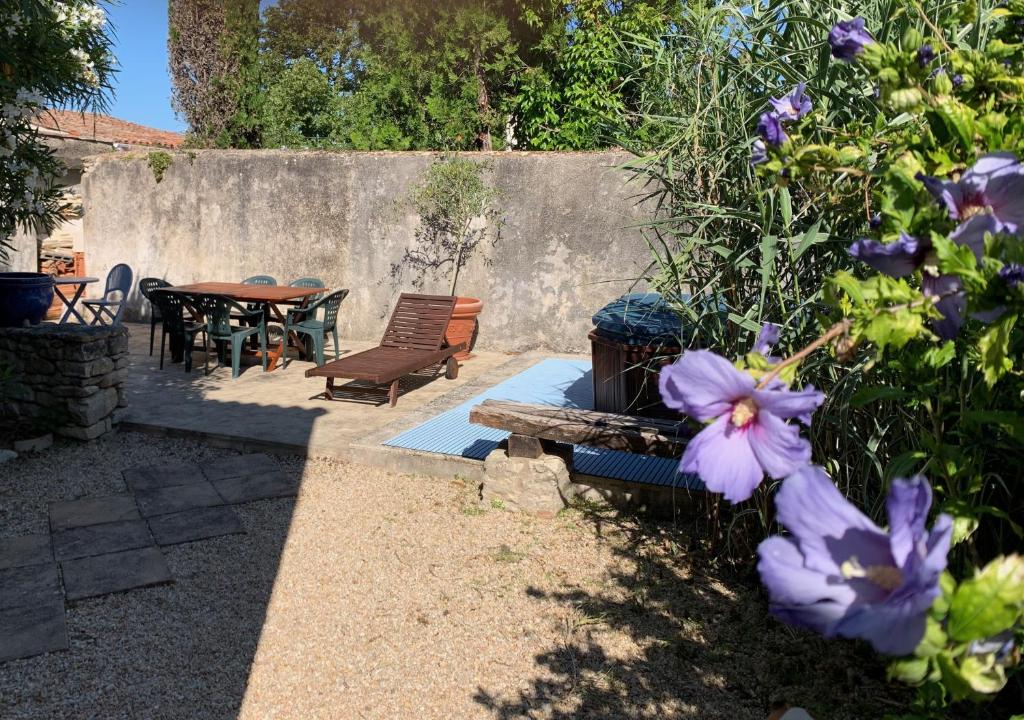 - un jardin avec une table, des chaises et des fleurs violettes dans l'établissement Maison de pays au centre du village, à Saint-Martin-de-Ré