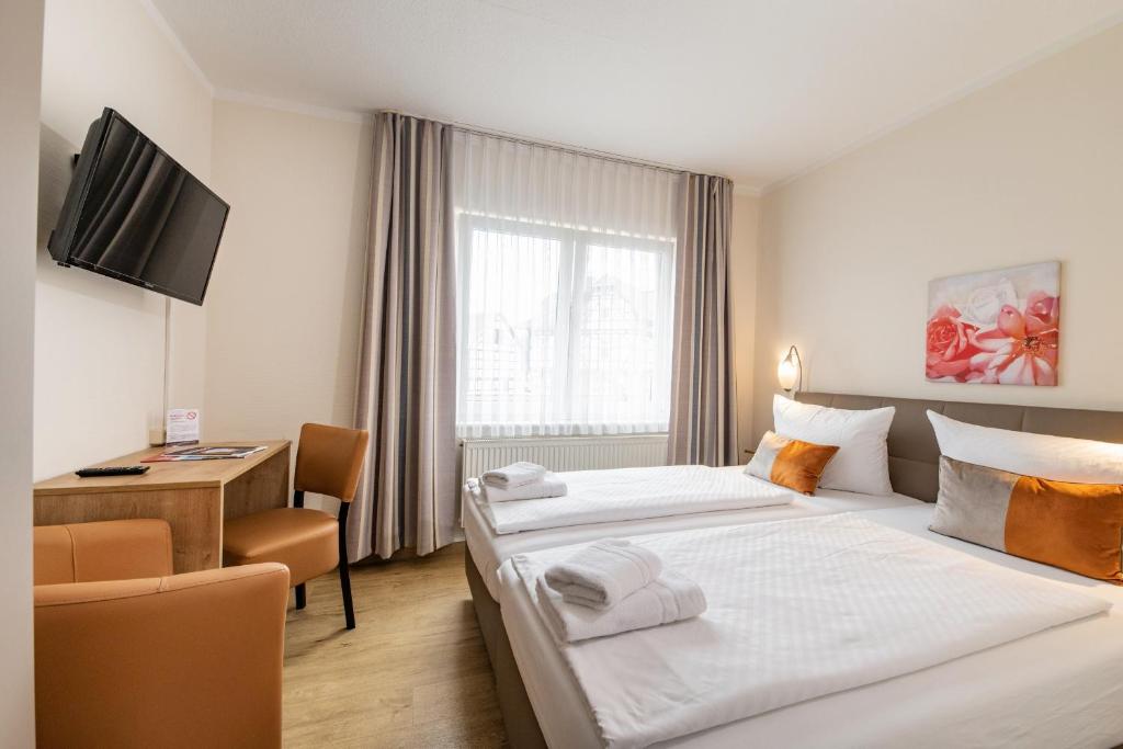 a hotel room with two beds and a desk at Hotel Bamberger Hof, garni in Eisenach