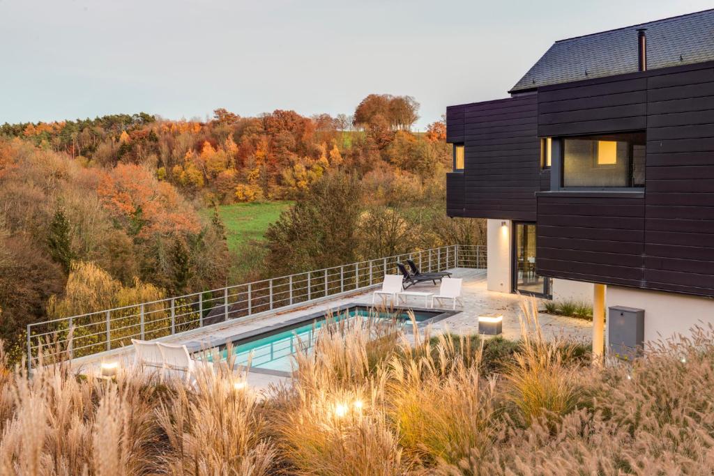 una casa nera con piscina e alberi di Chambres d’hôtes les Grisons a Houyet