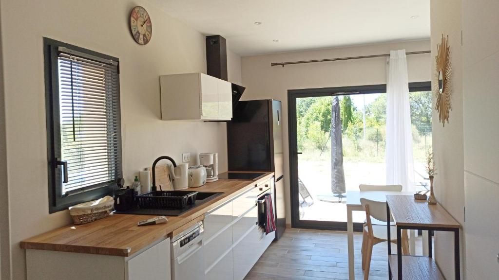 - une cuisine avec un évier et un comptoir avec une table dans l'établissement Maison d'hôtes calme proche village, à Bédoin