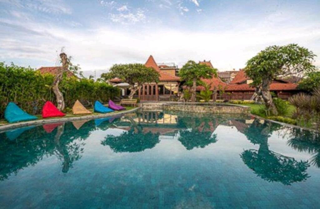 a swimming pool with colorful chairs in front of a house at DAMAI in Canggu