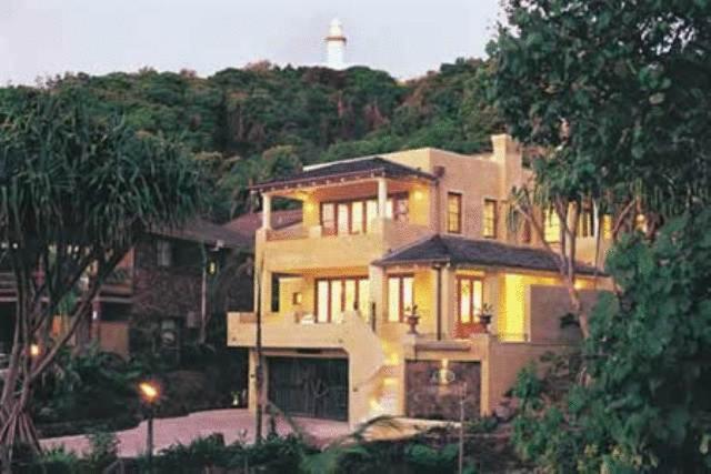 a large house with a lighthouse in the background at Victoria's At Wategos in Byron Bay