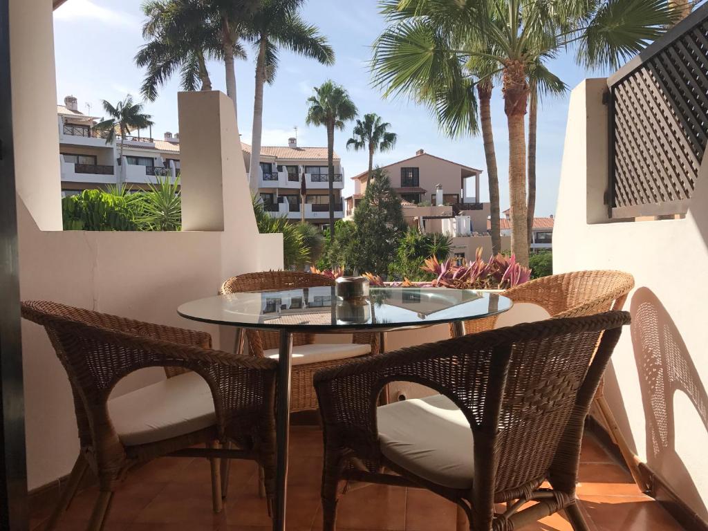 een tafel en stoelen op een balkon met palmbomen bij Royal park albatros bonito apartamento Golf del Sur in San Miguel de Abona