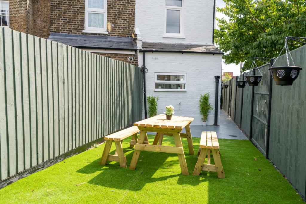 a picnic table and two benches in a backyard at Stunning and spacious house, with Free Parking and huge Garden, 5 Min to metro in London