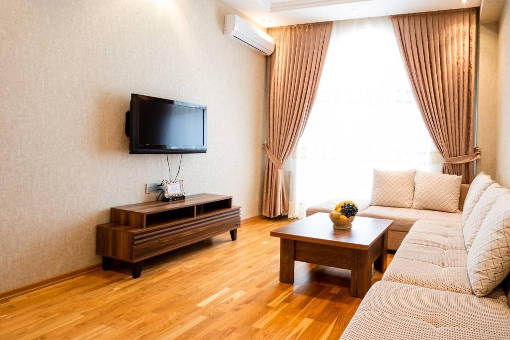 sala de estar con sofá y TV de pantalla plana en Просторная квартира Баку, en Baku