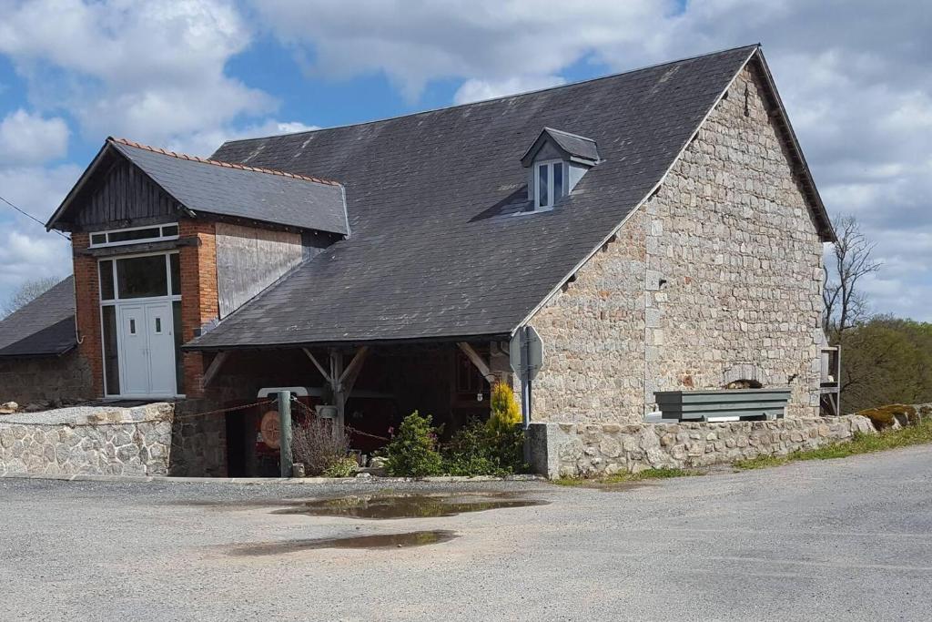 een groot bakstenen gebouw met een witte deur en een bank bij Charming 2-Bed Cottage within Barn in Merinchal in Mérinchal