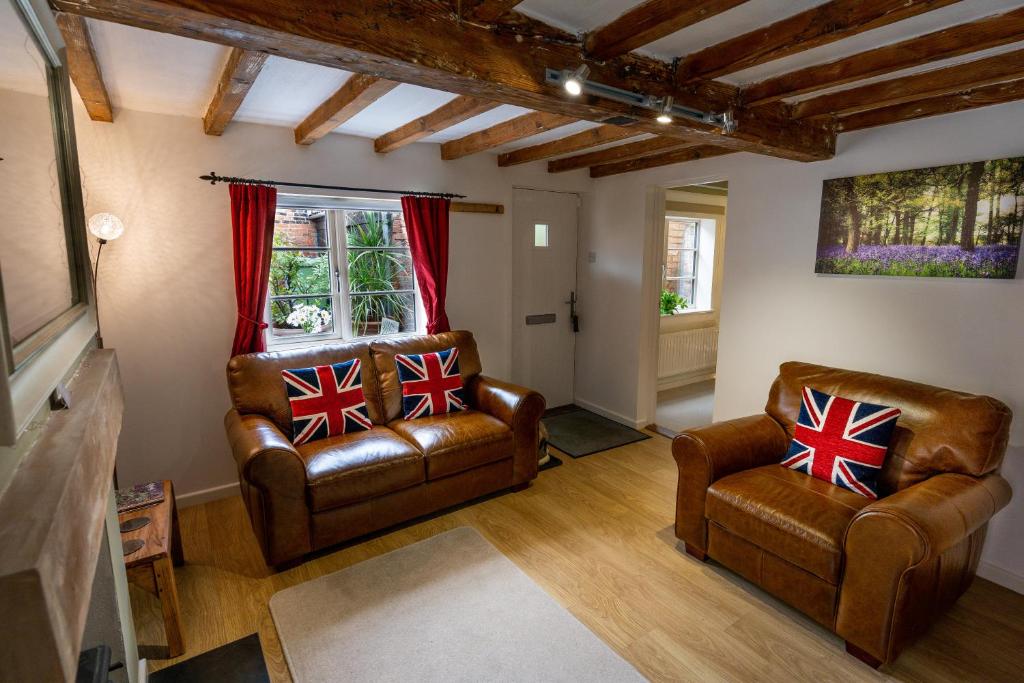 a living room with two leather chairs and a window at Southwell Holiday Cottage - Lavender Cottage in Southwell