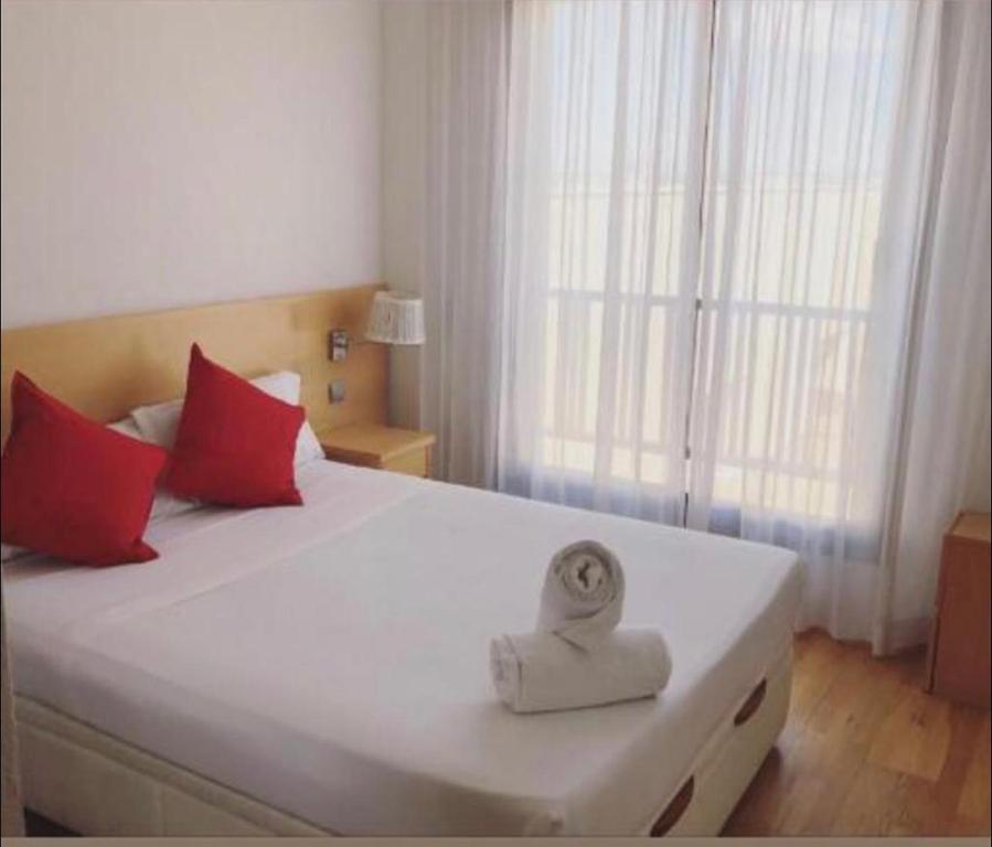 - une chambre avec un grand lit blanc et des oreillers rouges dans l'établissement Airport Madrid suites apartments Belfast 13, à Madrid