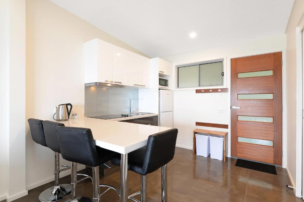 a kitchen with a table and black chairs at Seafarers Getaway in Apollo Bay
