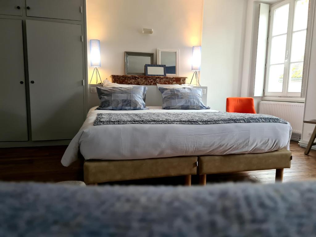 a bedroom with a large bed and two windows at Le Relais de l'endormie in Nogent-sur-Seine