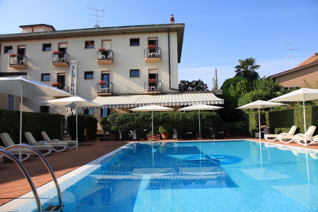 einen Pool mit Stühlen und Sonnenschirmen neben einem Gebäude in der Unterkunft Albergo Ristorante Papa in Peschiera del Garda