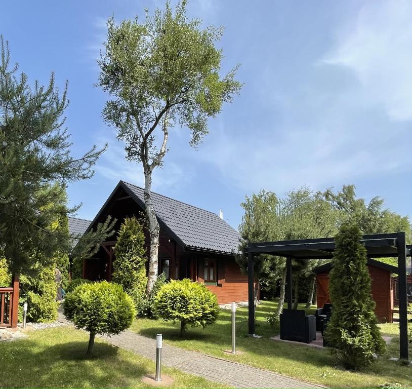 a house with a tree in front of it at Domki Pod Brzozami in Dźwirzyno