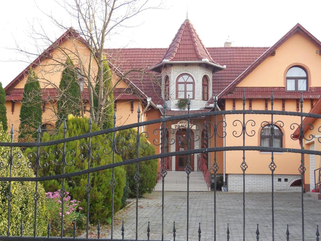 une grande maison avec une clôture devant elle dans l'établissement Hegyi Panzió, à Szilvásvárad