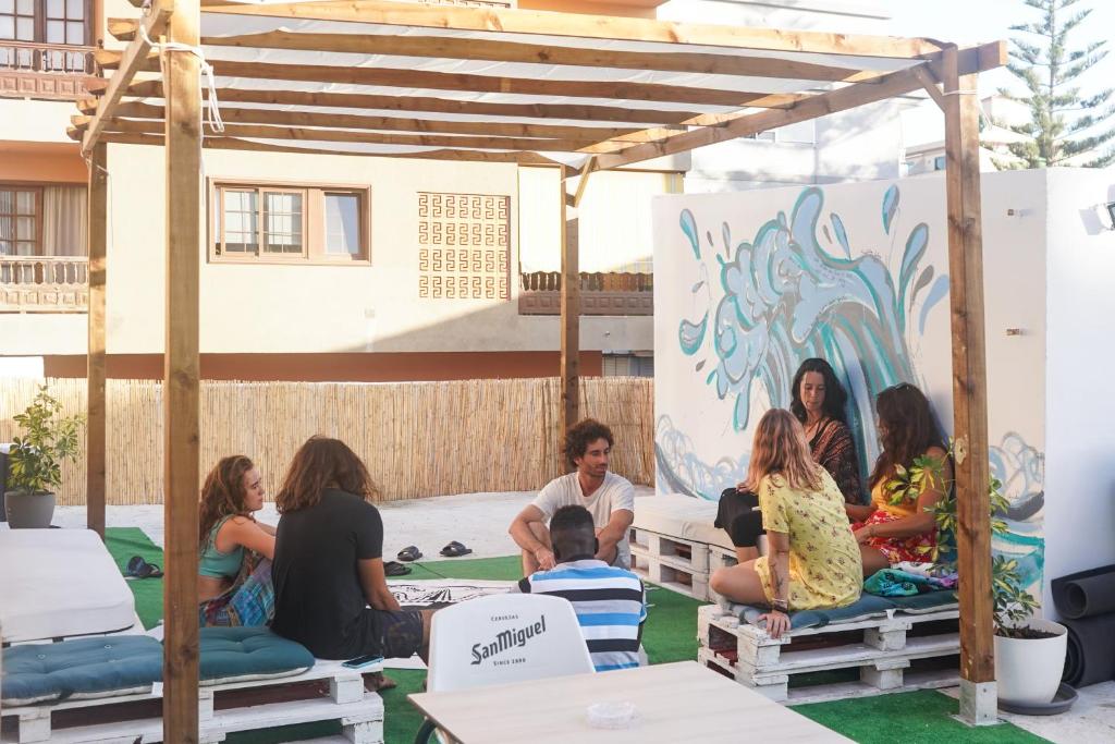 Un groupe de personnes assises sur des bancs sous une pergola dans l'établissement Single Fin Hostel, à Arona