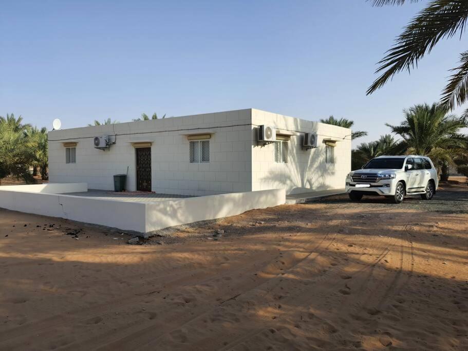 Spacious Farm Stay with 3 bedroom & relaxing view في Remah: سيارة بيضاء متوقفة أمام منزل