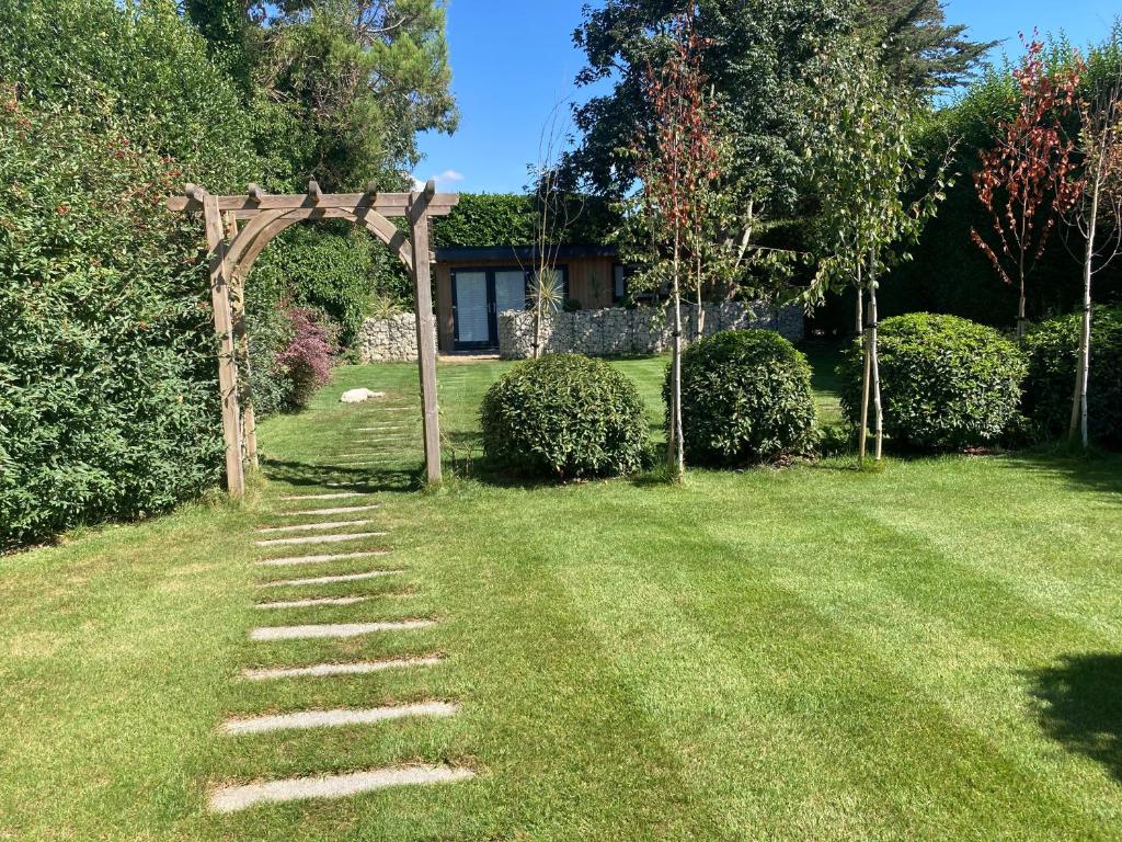 a garden with an arch and a path in the grass at Delightful self contained let in a village setting in Merston