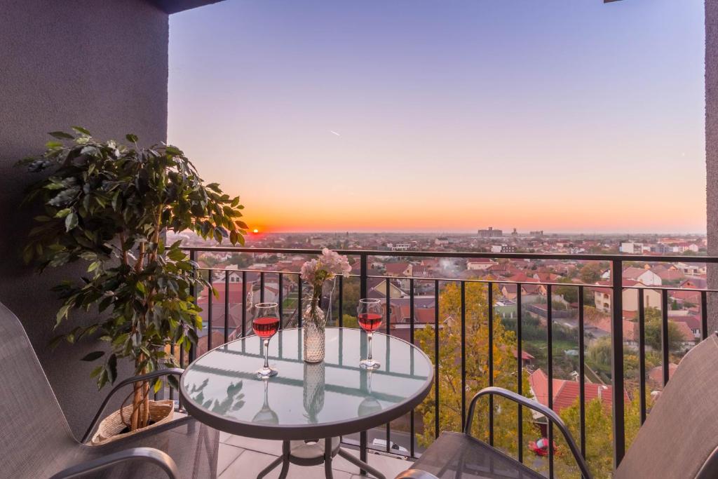 einen Balkon mit einem Tisch und 2 Gläsern Wein in der Unterkunft Talida's apartment colorful and brightnes in Oradea