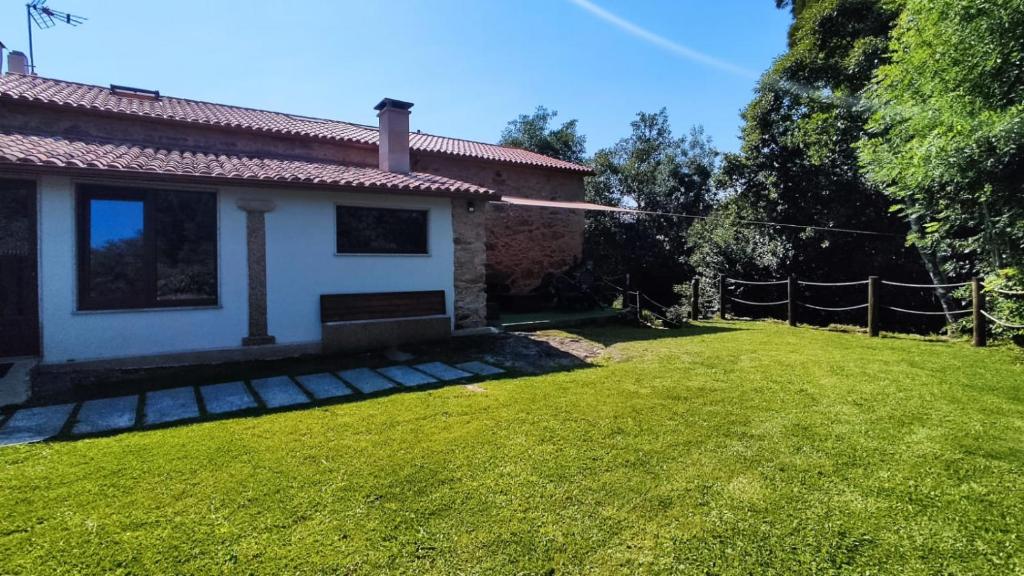 a backyard of a house with a grass yard at Alojamiento rústico paseo fluvial río Coroño, Boiro in Boiro
