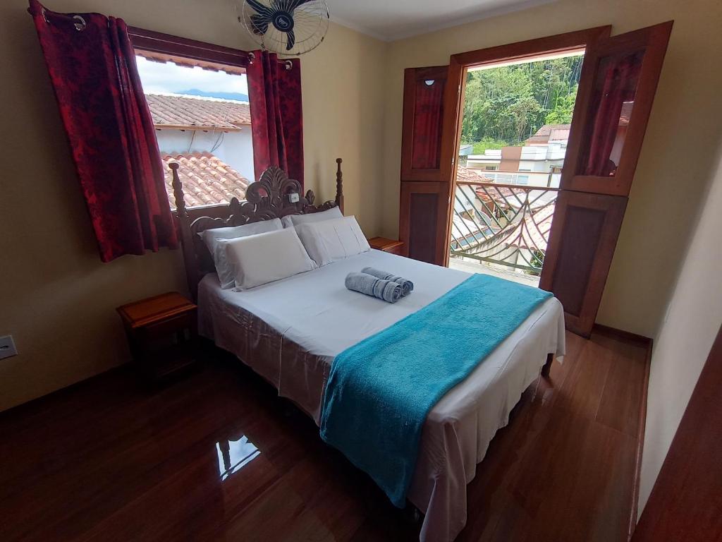 een slaapkamer met een bed en een groot raam bij Casa com piscina em condomínio in Paraty